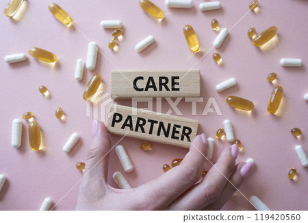 Care Partner symbol. Concept word. Care Partner on wooden blocks. Doctor Hand. Beautiful pink background with pills. Medicine and Care Partner concept. Copy space 119420560
