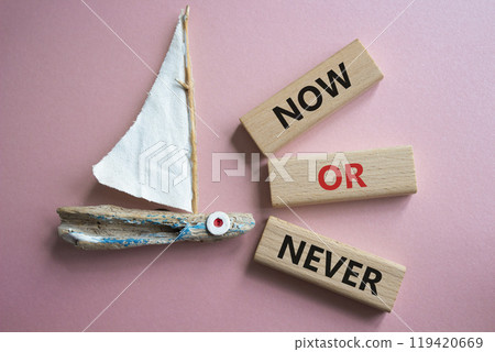 Now or Never symbol. Concept words Now or Never on wooden blocks. Beautiful pink background with boat. Business and Now or Never concept. Copy space Now or Never symbol. Concept words Now or Never on wooden blocks. Beautiful pink background with boat. Business and Now or Never concept. Copy space 119420669