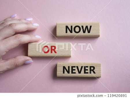 Now or Never symbol. Concept words Now or Never on wooden blocks. Businessman hand. Beautiful pink background. Business and Now or Never concept. Copy space Now or Never symbol. Concept words Now or Never on wooden blocks. Businessman hand. Beautiful pink background. Business and Now or Never concept. Copy space 119420891