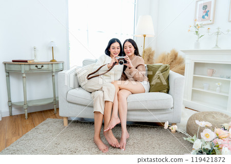 Beautiful Asian women enjoy to look picture from camera together and stay in living room. 119421872