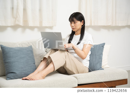 一位女士在客廳的沙發上使用電腦 一位女士在客廳的沙發上使用電腦 119422656