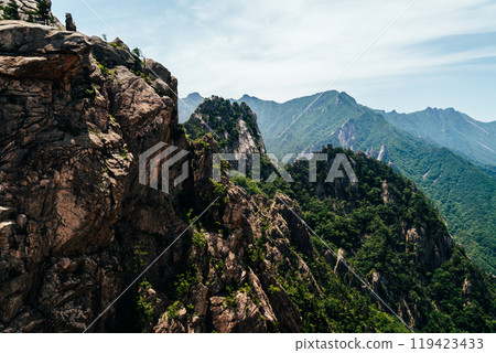 Majestic mountain landscape in Seoraksan National Park showcasing lush greenery and rocky cliffs under a clear blue sky Majestic mountain landscape in Seoraksan National Park showcasing lush greenery and rocky cliffs under a clear blue sky 119423433