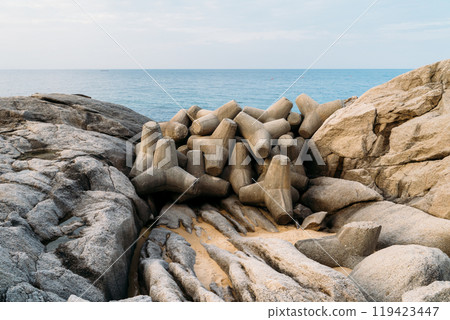 Coastal rock formations and concrete blocks along South Koreas shoreline during a calm afternoon at the beach Coastal rock formations and concrete blocks along South Koreas shoreline during a calm afternoon at the beach 119423447