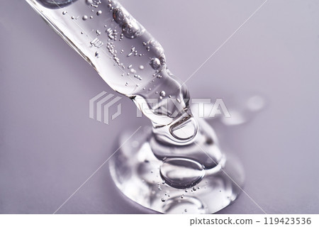 Pipette with facial serum pouring out of it on purple background. 119423536
