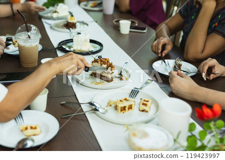 Woman hand cutting slice of cake  cake with group of friends meeting at cafe. 119423997