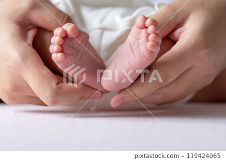 A mother gentle hands cradle her baby tiny feet, capturing a tender moment of warmth and love, with soft, delicate toes resting in her caring embrace. A mother gentle hands cradle her baby tiny feet, capturing a tender moment of warmth and love, with soft, delicate toes resting in her caring embrace. 119424065