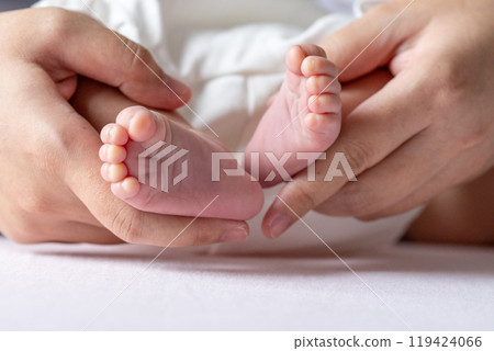 A mother gentle hands cradle her baby tiny feet, capturing a tender moment of warmth and love, with soft, delicate toes resting in her caring embrace. A mother gentle hands cradle her baby tiny feet, capturing a tender moment of warmth and love, with soft, delicate toes resting in her caring embrace. 119424066