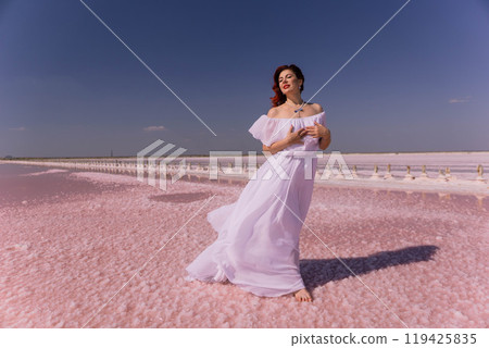 Woman White Dress Pink Salt Flats Smiling Woman in White Dress on Pink Salt Flats under Blue Sky. 119425835