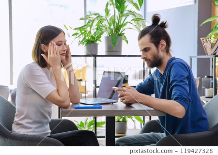 Serious sad upset young couple sitting together in cafeteria Serious sad upset young couple sitting together in cafeteria 119427328