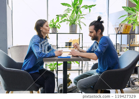 Young man woman sitting together in cafe coffee shop, talking Young man woman sitting together in cafe coffee shop, talking 119427329