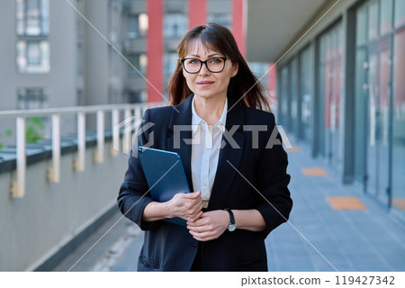Mature confident business woman with digital tablet in black suit outdoors 119427342