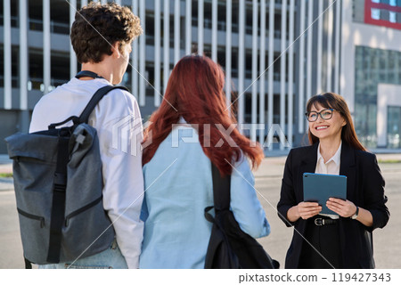 Business woman with digital tablet talking working with group of youth, outdoor 119427343