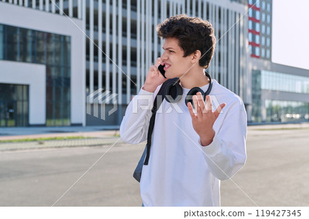 Young serious guy talking on mobile phone, modern city background, urban style 119427345