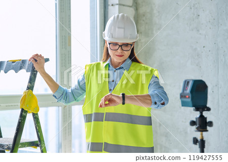 Technical profession woman in protective vest helmet working on construction Technical profession woman in protective vest helmet working on construction 119427555