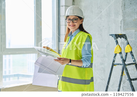 Woman in safety vest hard hat with plan on new residential or commercial real estate site 119427556