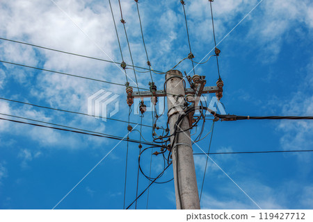 Electric pole power lines outgoing electric wires againts on cloud blue sky. 119427712