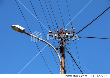 Electric pole power lines outgoing electric wires againts on cloud blue sky. 119427713