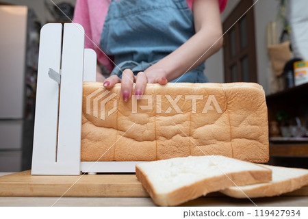 A woman's hands cutting bread using a bread slicer A woman's hands cutting bread using a bread slicer 119427934