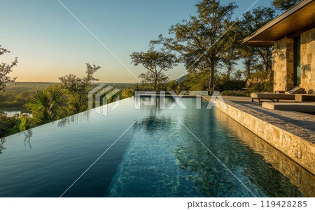 Elegant infinity pool overlooking a lush forest landscape at sunset, featuring a modern stone patio and loungers for ultimate relaxation 119428285