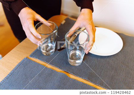 female hands clearing glass glasses from table 119428462