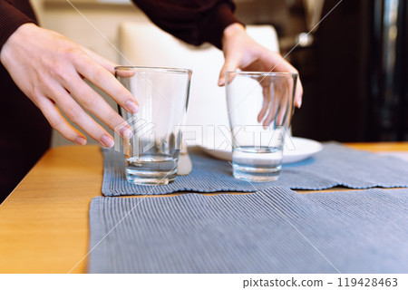 female hands clearing glass glasses from table 119428463
