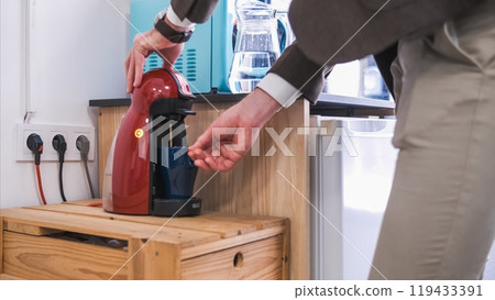 Crop businessman filling coffee in mug from machine in office canteen 119433391