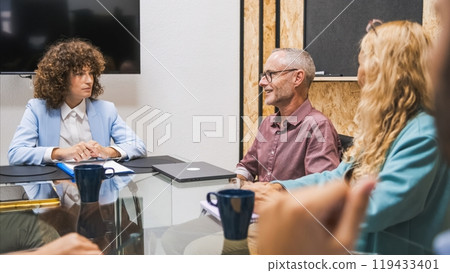 Happy mature businessman discussing with female colleagues during meeting Happy mature businessman discussing with female colleagues during meeting 119433401