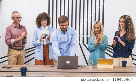 Happy team applauding for businessman using laptop in conference room 119433404