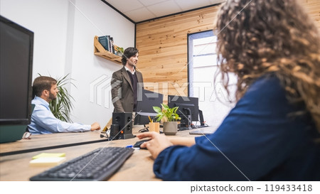 Businessman standing and presenting during a meeting in a modern office. Businessman standing and presenting during a meeting in a modern office. 119433418