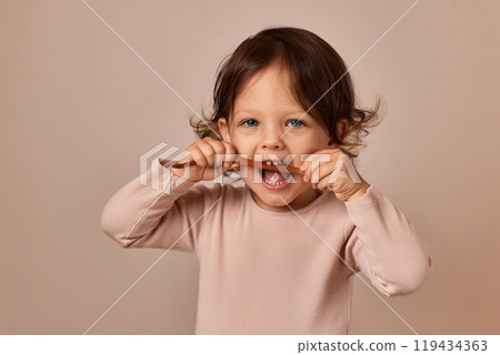 cute child girl bites fruit pastille on beige background. healthy baby food. cute child girl bites fruit pastille on beige background. healthy baby food. 119434363