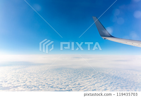 View from the airplane window at a beautiful cloudy sky and the airplane wing View from the airplane window at a beautiful cloudy sky and the airplane wing 119435703