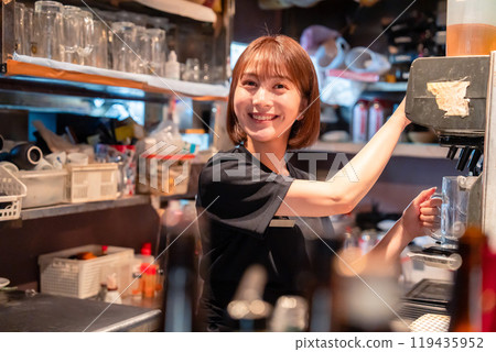 A female waiter using a beer server at a restaurant 119435952