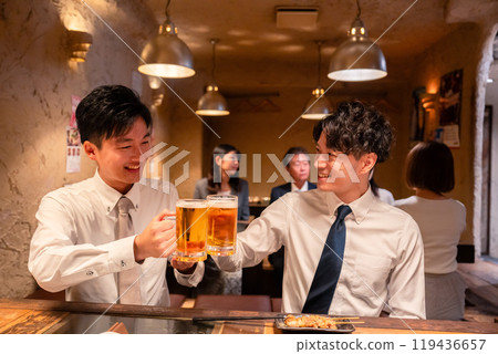 Two young businessmen drinking beer at an izakaya 119436657