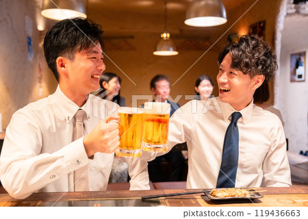Two young businessmen drinking beer at an izakaya 119436663