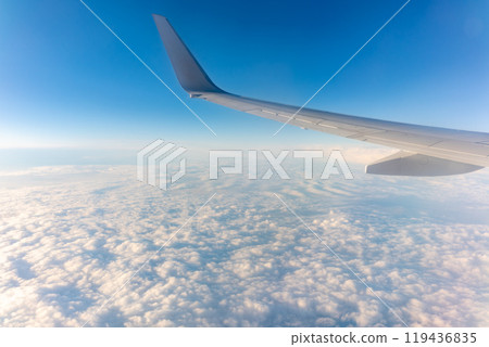 Beautiful salmon dawn and the wing of an airplane above the clouds. 119436835
