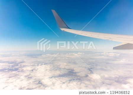 View from the airplane window at a beautiful cloudy sky and the airplane wing 119436852