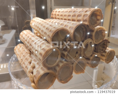 Waffle rolls with condensed milk cream lie in a pile in the window of a cafe store 119437019