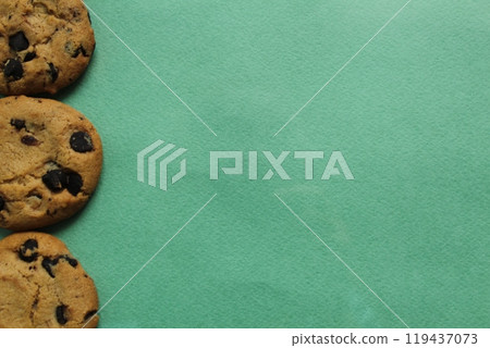 Chocolate chip cookie background on a green background with space for copyspace text. Food background 119437073