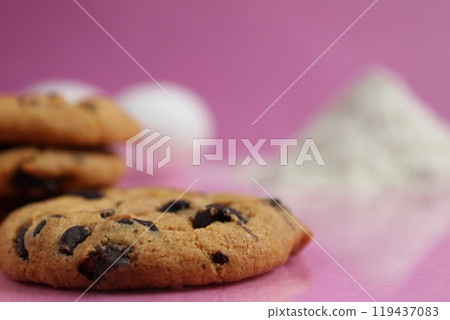 Chocolate crust pastry on a background of flour and eggs on a pink background with space for text. Background for a cookie recipe 119437083