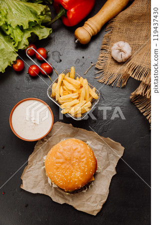 Top view of burger, fries, and sauce on rustic background. Perfect fast-food meal for any occasion 119437430