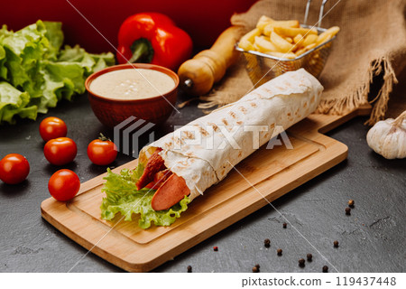 Grilled sausage wrap with fresh lettuce, a perfect quick snack or meal for on-the-go moments 119437448