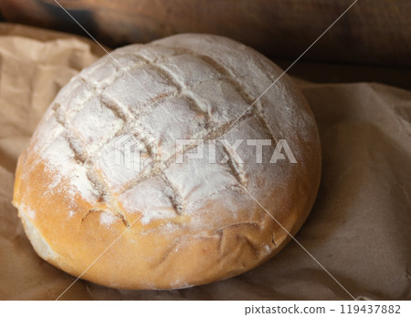 Close-up at 45 degrees of a loaf of bread on rustic paper. 119437882
