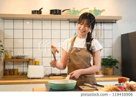 Smiling young asian woman preparing breakfast in a cozy kitchen 119438906