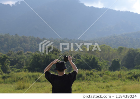 Male traveller taking pictures of landscape with a digital camera in a field. Travel lifestyle concept Male traveller taking pictures of landscape with a digital camera in a field. Travel lifestyle concept 119439024