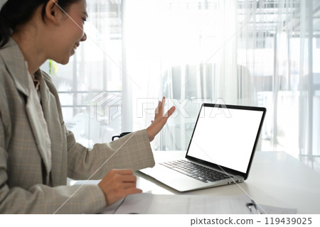 Cheerful young entrepreneur having virtual video call online consultation on laptop at office desk Cheerful young entrepreneur having virtual video call online consultation on laptop at office desk 119439025
