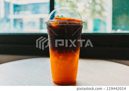 Plastic cup of Iced Orange Americano coffee on the table. 119442014