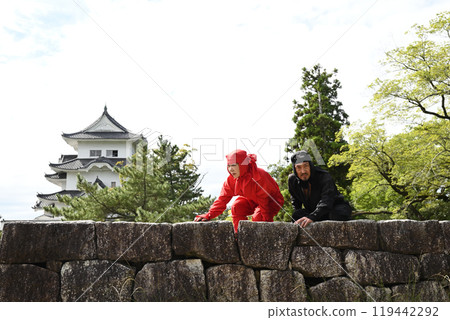 女忍者和忍者從石牆頂部爬上來 119442292