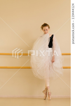 Ballet dancer showcases graceful stance in serene studio setting 119444124