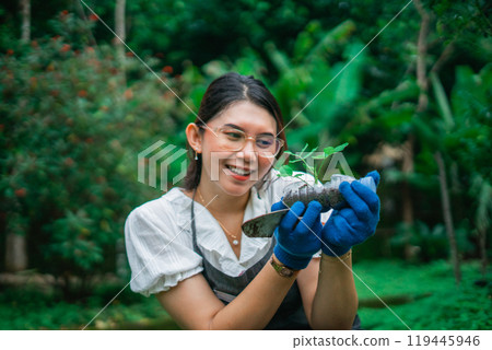 happy asian woman looking at her seedling in plastic bottle pot 119445946