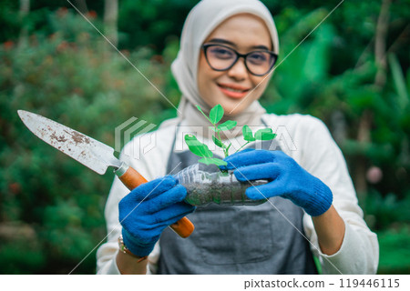 hijab woman holding green seedling in reused plastic bottle hijab woman holding green seedling in reused plastic bottle 119446115